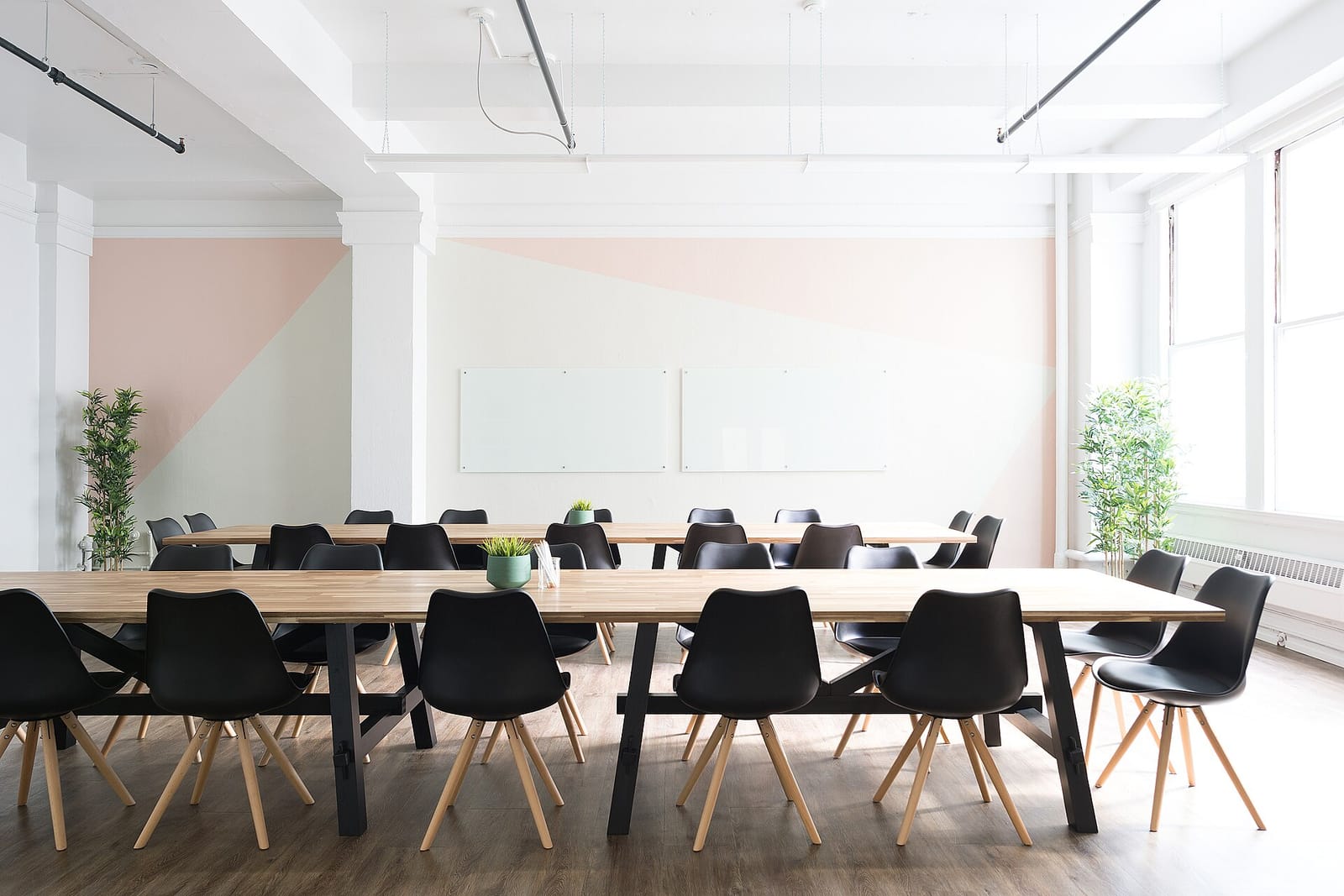 A bright meeting room with a long table, chairs and a whiteboard