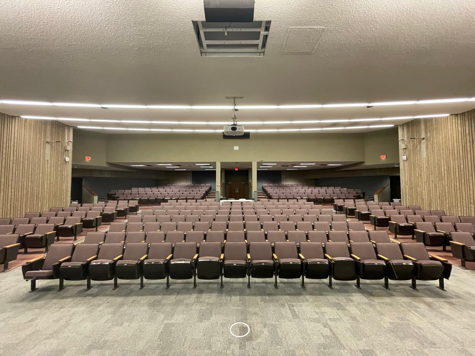 An empty university lecture hall with rows of seats facing the stage