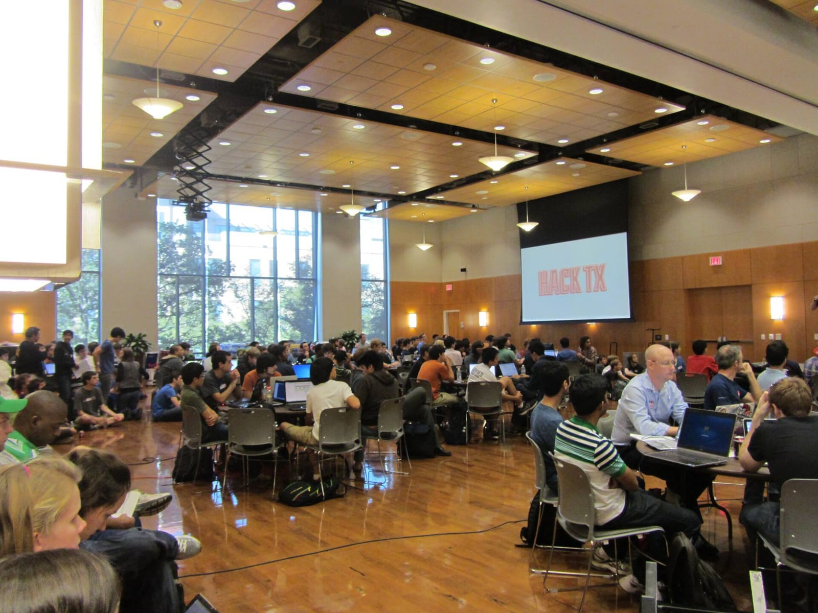 Teams of participants working on laptops in a large hall during the HackTX hackathon