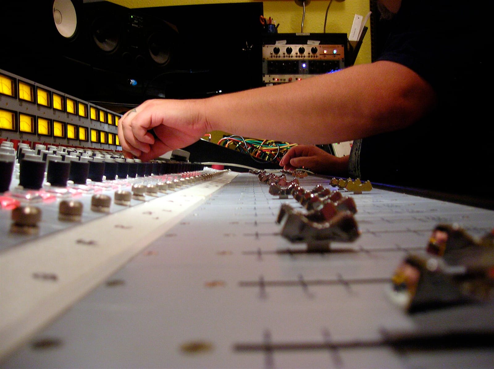 A sound engineer's hands adjusting faders on a mixing console in a recording studio