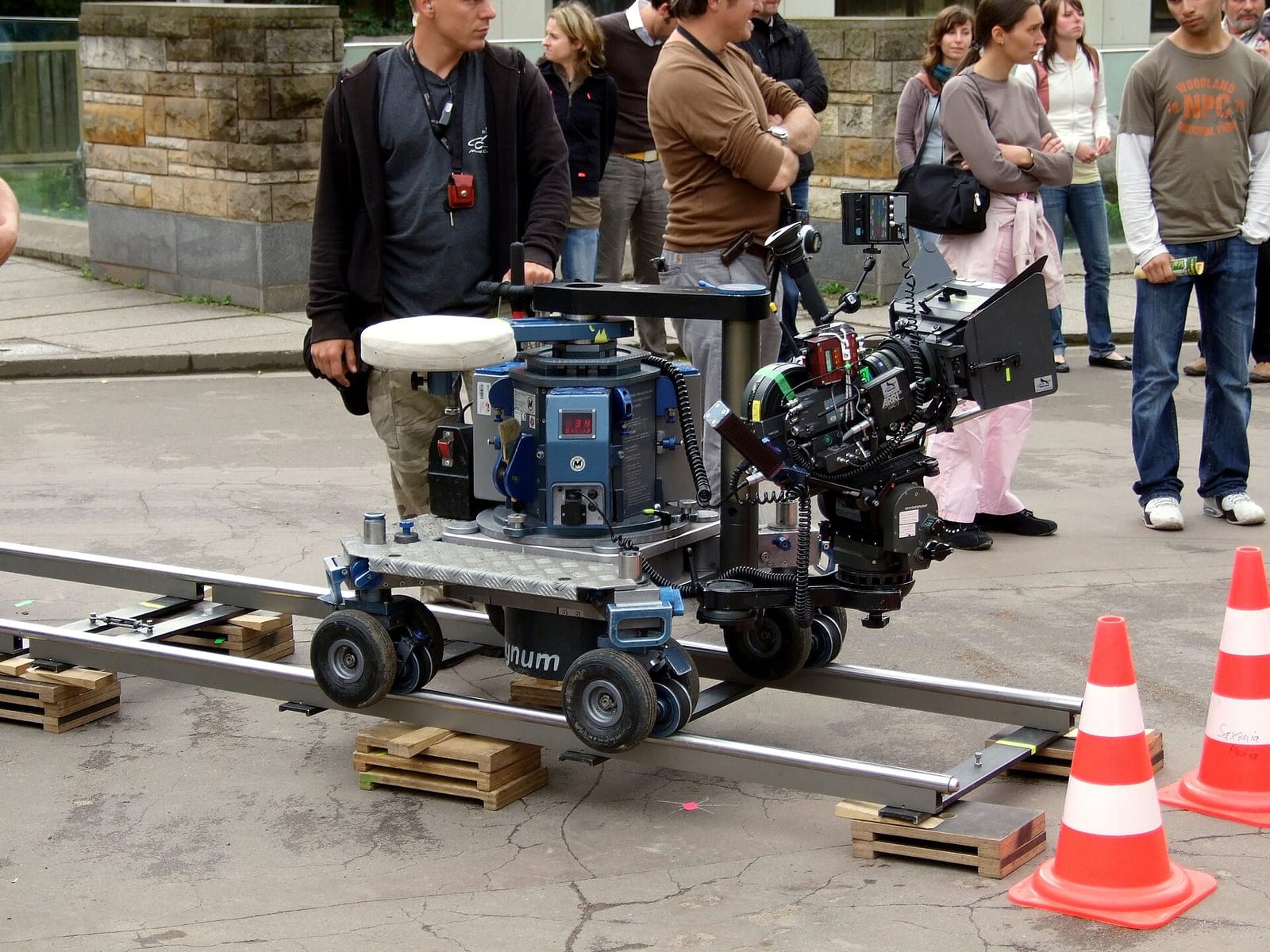 A film crew on location with a cinema camera mounted on a dolly track