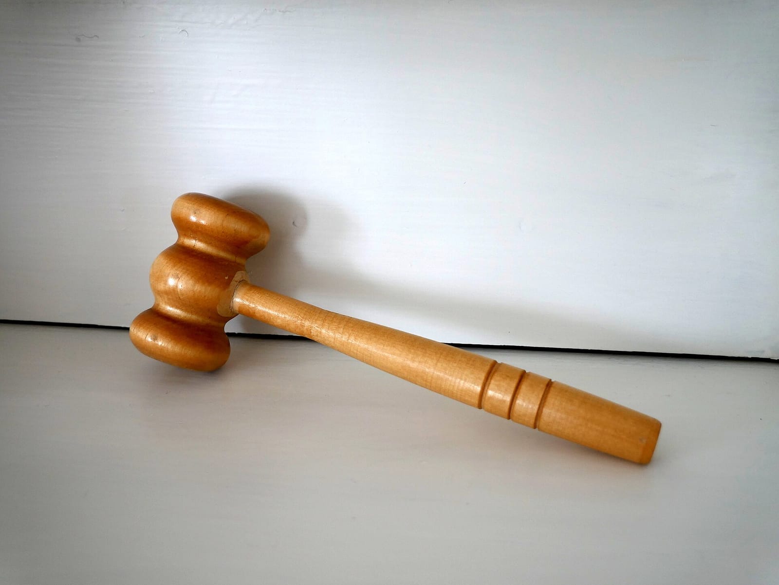A wooden gavel lying on a white surface