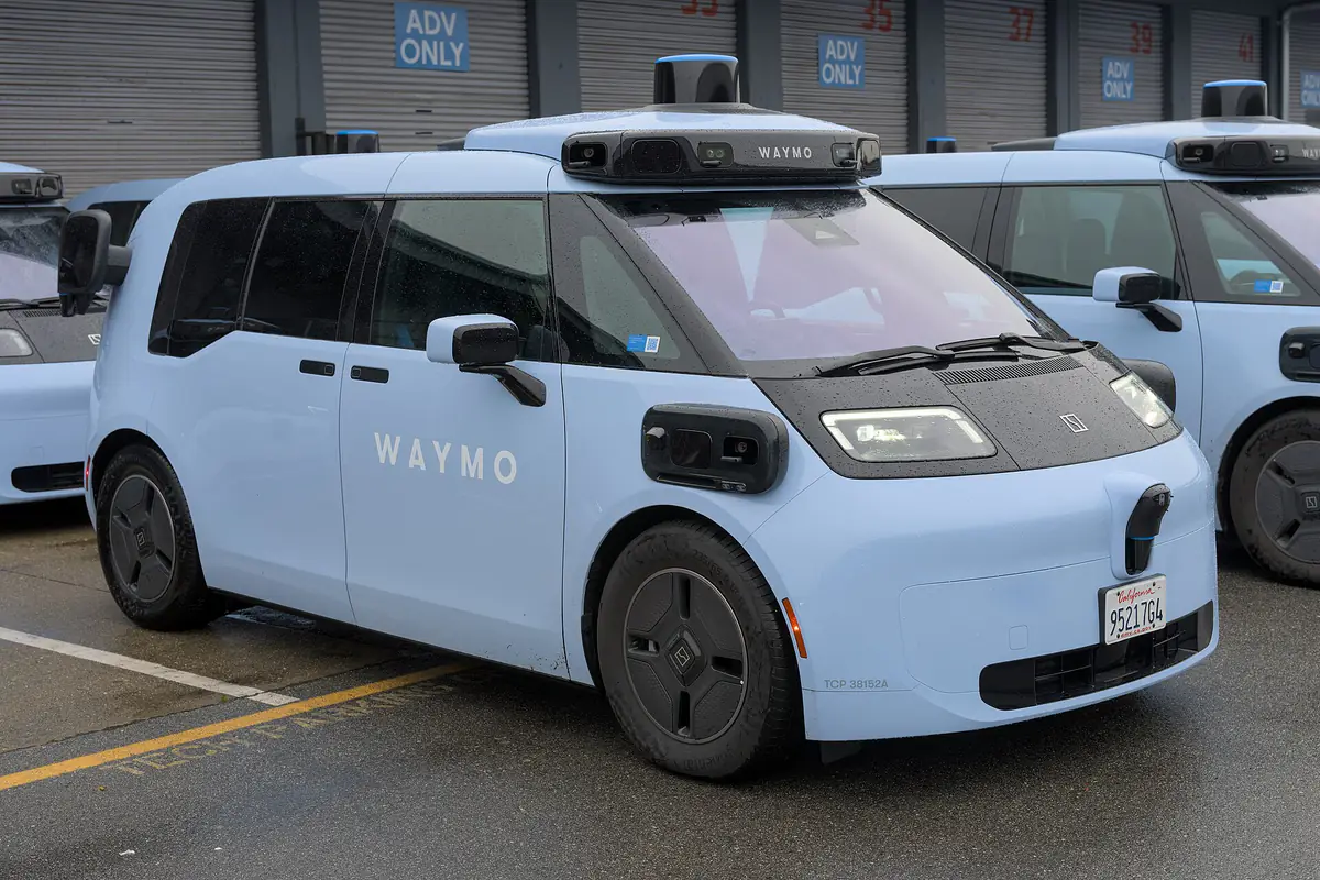 Light blue Waymo Zeekr robotaxis with roof-mounted sensors parked in a depot lot