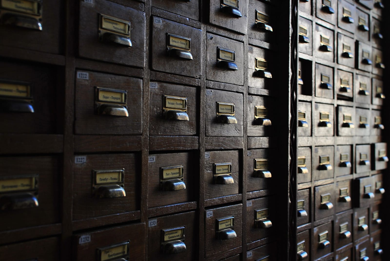 Rows of wooden library card catalogue drawers with brass label holders