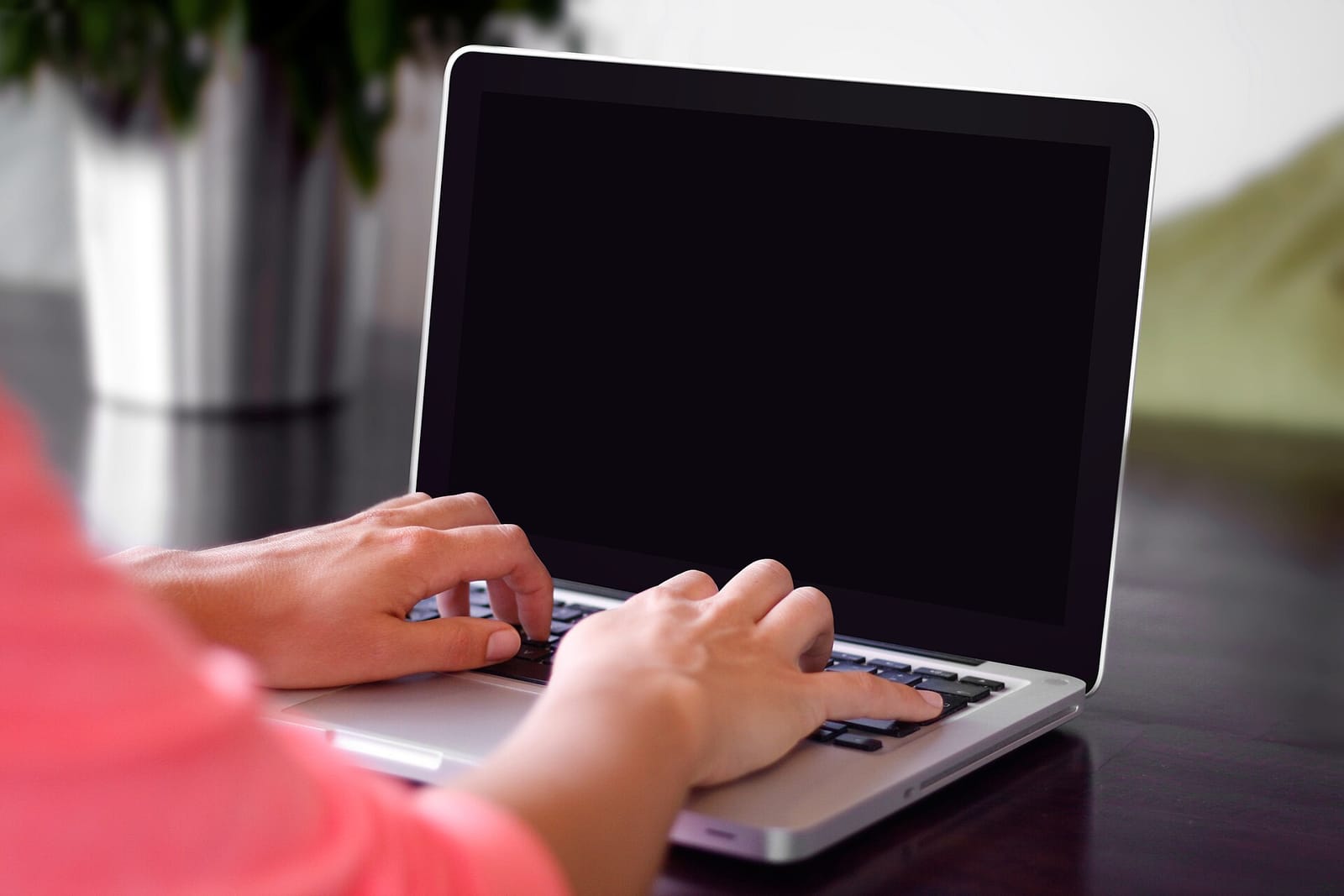 Person typing on a silver laptop on a desk