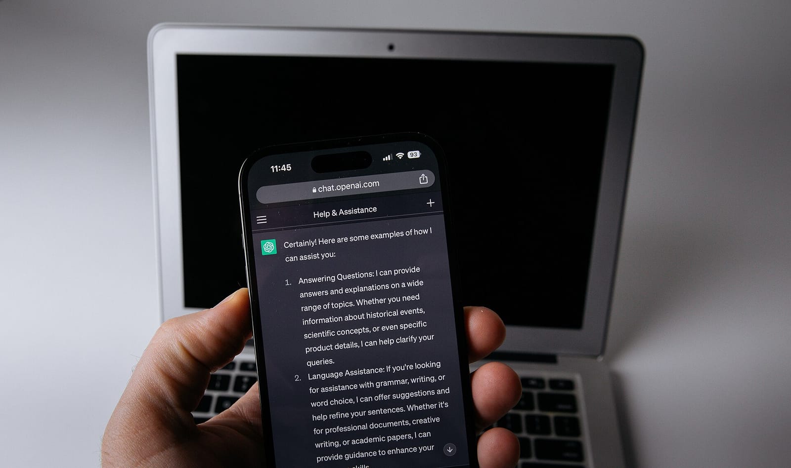 Smartphone showing the ChatGPT app placed in front of a laptop