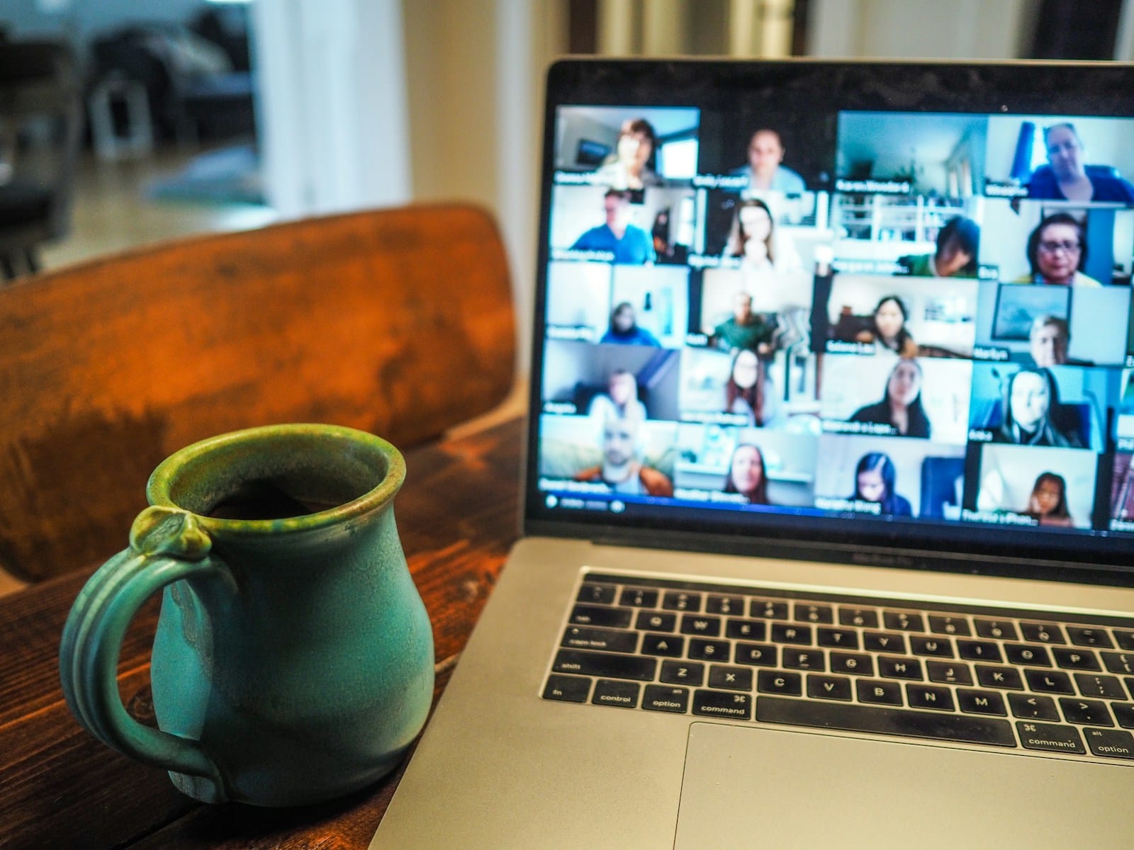 Laptop on a desk showing a video call with a grid of participants